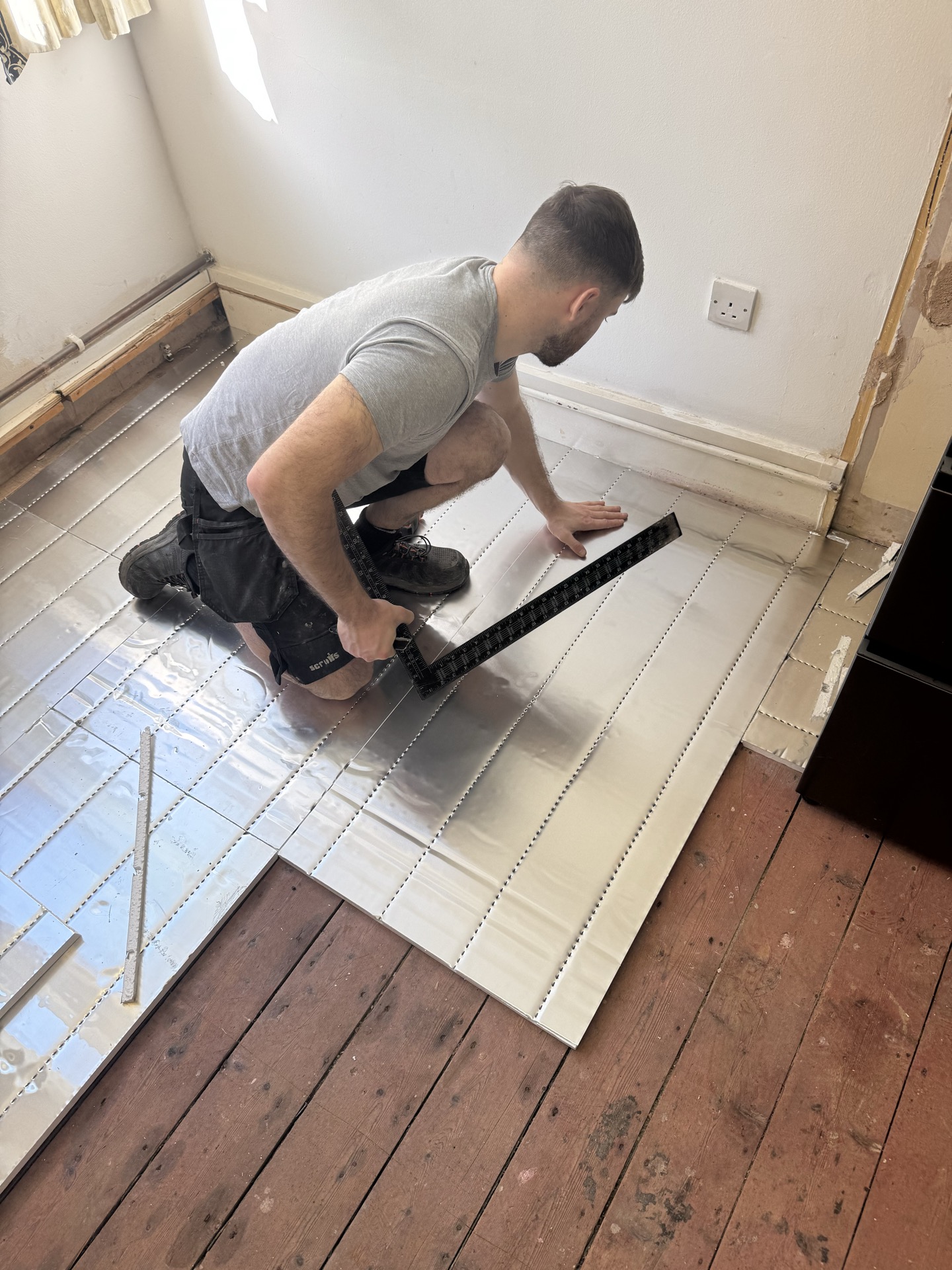 Jake clipping pipe channel into overlay panels over original timber boards