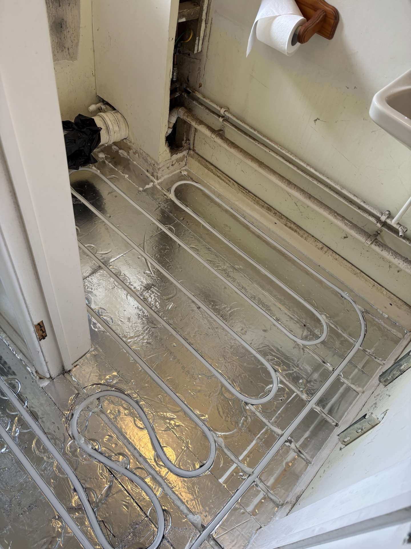 Retrofit underfloor heating routed around bathroom soil pipe